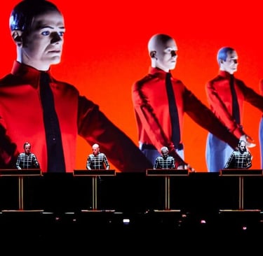 Iconic image of Kraftwerk standing at synthesizers with a rigid, robot-like performance style.