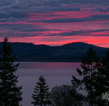 a sunrise sky with a pink sky and a mountain in the background overlooking a lake