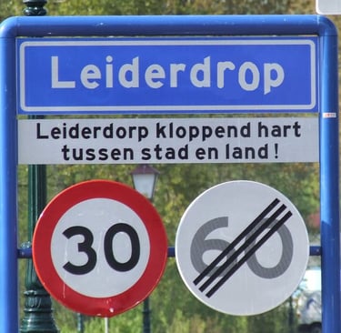 Blauw plaatsnaambord waarop 'Leiderdorp' is herschreven tot 'Leiderdrop', dat Jamie als kind las.