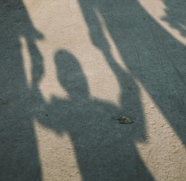 Schaduw van twee volwassenen met kind ertussen: verbinding en uitsluiting.