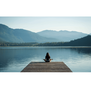 a woman sitting on a dock with mountains in the background