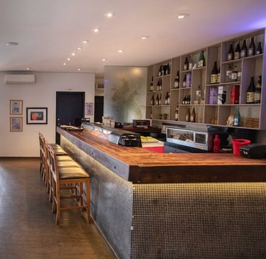 Balcão sushi bar do Kaizen e iluminação suave em ambiente contemporâneo
