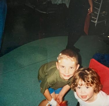 A photo of Chandy aged 6 with his younger sister. He is in Hospital and has a scar on his head. 