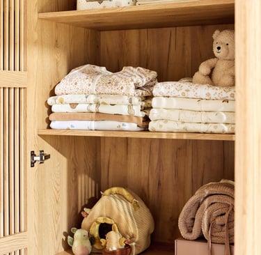 Photo of cupboard shelves with Jollein sleepsuits and toys