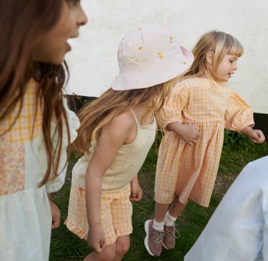 Photo from Wheat SS25 collection featuring 3 girls in orange checked dresses and outfits