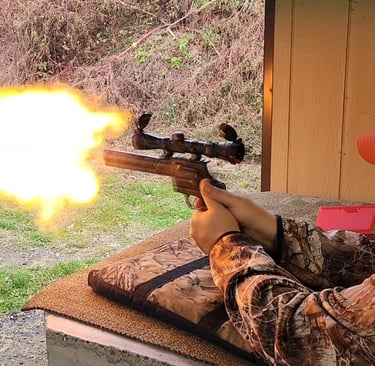 A hunter firing a scoped revolver at a shooting range with a large orange muzzle flash.