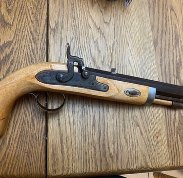 Custom Built muzzleloader pistol with a light wood stock on a rustic oak table.