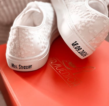 a pair of white sneakers with a red box on top of a red box