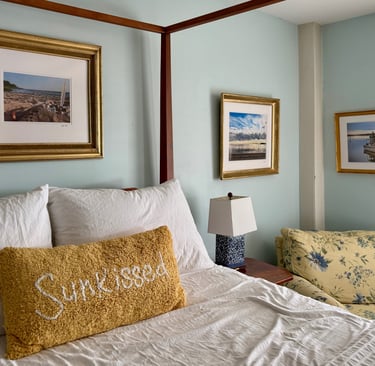 Ensuite bedroom with 4-poster bed, water views, and original framed artwork.