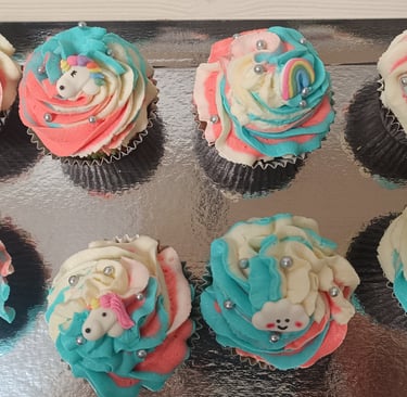 a tray of cupcakes with a teddy bear on top