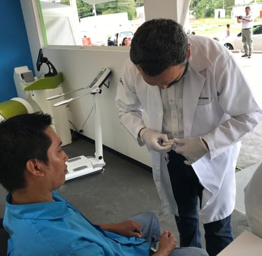 Médico realizando una prueba médica a un paciente en una unidad móvil de salud ocupacional.