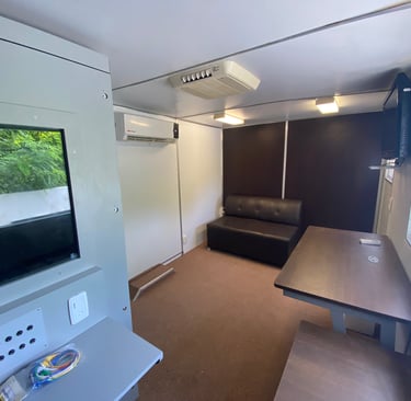 Interior de unidad médica móvil equipada con cabina audiométrica y mobiliario para atención médica.