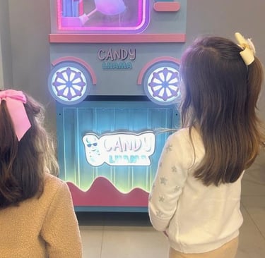duas meninas observam o algodão doce ser produzido na máquina