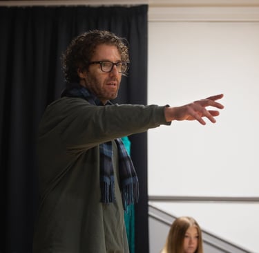 Film Director James Rose in a green jacket and scarf standing in front of actors
