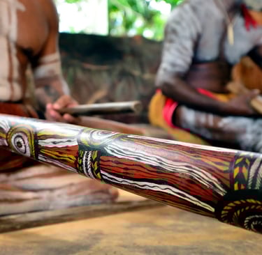 two Aboriginal men 1 playing a didgeridoo 1 playing clapsticks