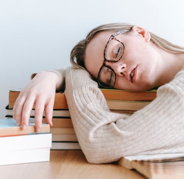 a woman is sleeping on a stack of books fatigue due to vitamin b12
