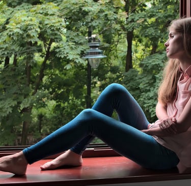 a woman sitting on a window sill with her feet on the floor