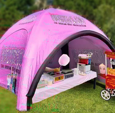 Pink inflatable event tent with popcorn machine and cotton candy station for party rentals.