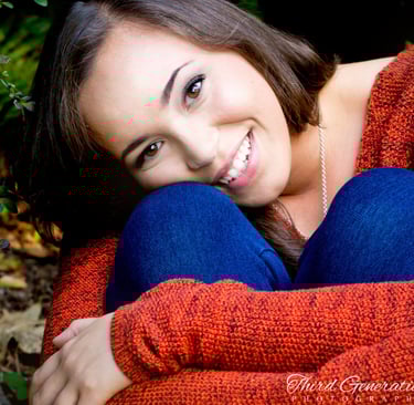 a woman in a red sweater and jeans sitting on a bench