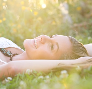 a woman laying on the grass in the sun