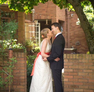 a bride and groom kissing in front of a brick wall