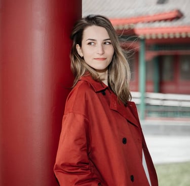 a woman in a red coat standing in front of a red pillar