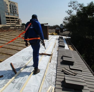 Environmental Pro Construction installing SABS-compliant roof sheeting under safety harness in West 