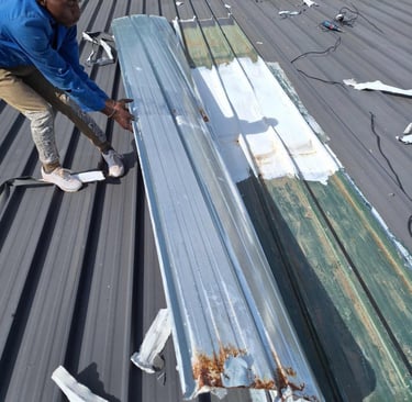 Roof with widespread storm damage, showing loose and bent metal sheets.