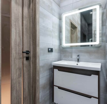 Photo of a modern bathroom vanity with illuminated mirror and grey tiled