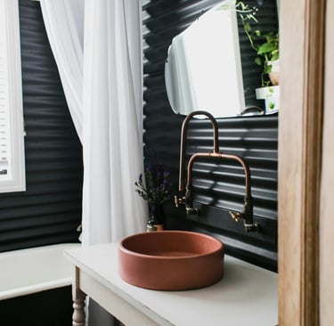 Modern bathroom with round basin and copper tap against dark panel wall