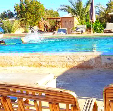 Gutt som svømmer i bassenget nær sjøen og bungalow på beduinstjernen Egypt