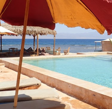  et basseng på stranden med parasoller og stoler 