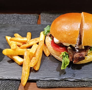 Gourmet steak burger on a brioche bun served with crispy french fries and ketchup on a slate plate.