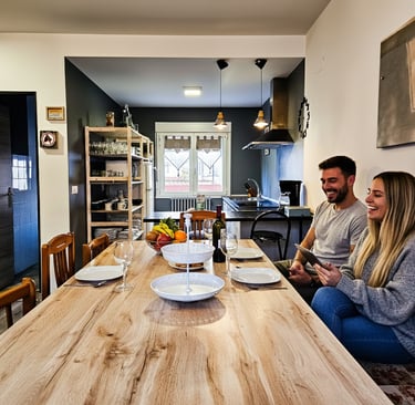 Living room and kitchen of a tourist house, a man and woman sitting at a table with plates of food