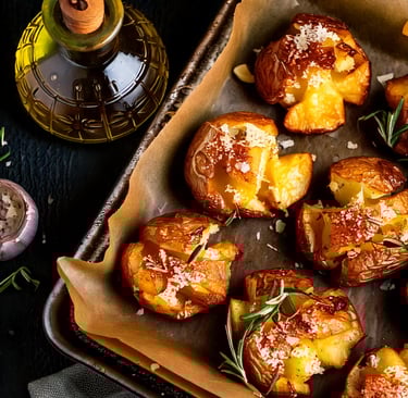 a tray of baked potatoes with rosemary sprigs