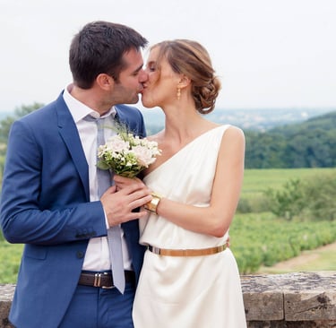 Couple de jeunes mariés qui s'embrasse en tenant leur bouquet de mariage à Dijon.