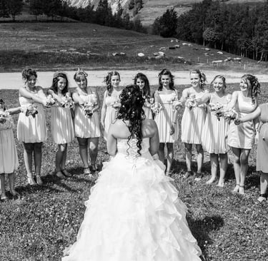 Photo en noir et blanc des demoiselles d'honneur avec des bouquets autour de la mariée