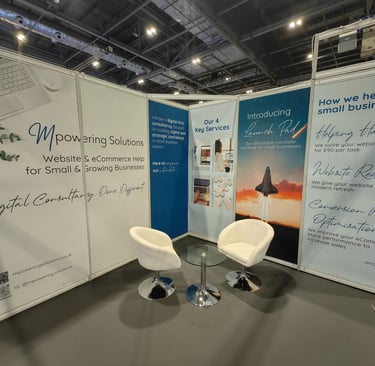 The 3x3 space Mpowering Solutions had at the Business Show in 2025, with wall panels and white furniture
