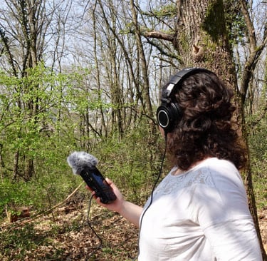 Federica doing some field recording in nature with headphones and a microphone