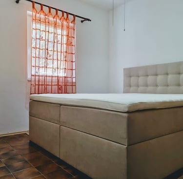 The photo shows a double bed and a window with a curtain in the apartment's bedroom.