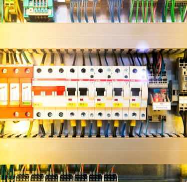 Industrial electrical control panel with circuit breakers, colorful wiring, and terminal blocks.