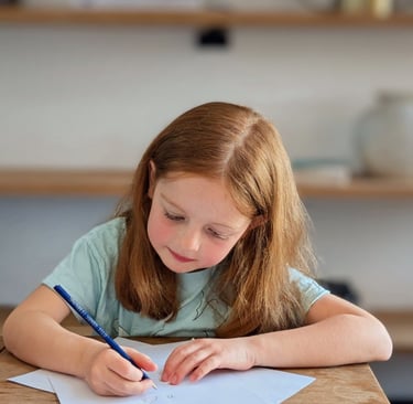 A young red-haired girl working for her key stage 2 tuition session on maths.