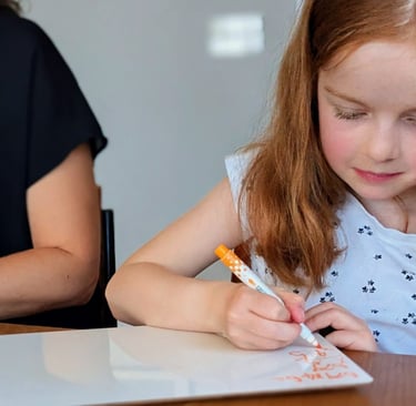 A young girl with red hair practicing math problems on a whiteboard for 11+ tutoring