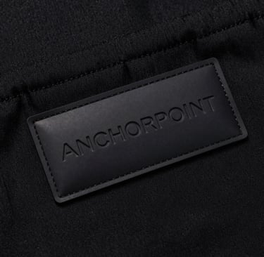 A sleek, minimalist workspace with a laptop, coffee cup, and anchorpoint branded notebook.