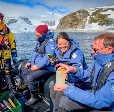 Researchers in blue parkas collect water samples on a boat during an Antarctica expedition.
