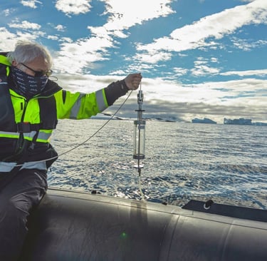 Researcher collecting ocean water samples with a Niskin bottle in Antarctica.