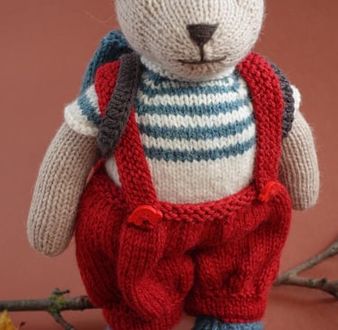 a teddy bear in a knitted sweater and overalls