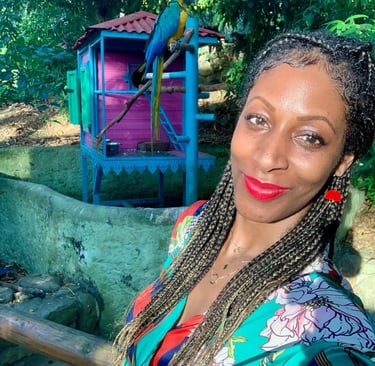 A woman with long hair in the Botanic Garden in Deshaies Guadeloupe and a parrot behind her