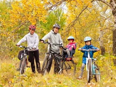 family riding bikes in the fall leaves