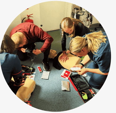 A group of learners completing practical CPR and AED training with manikins